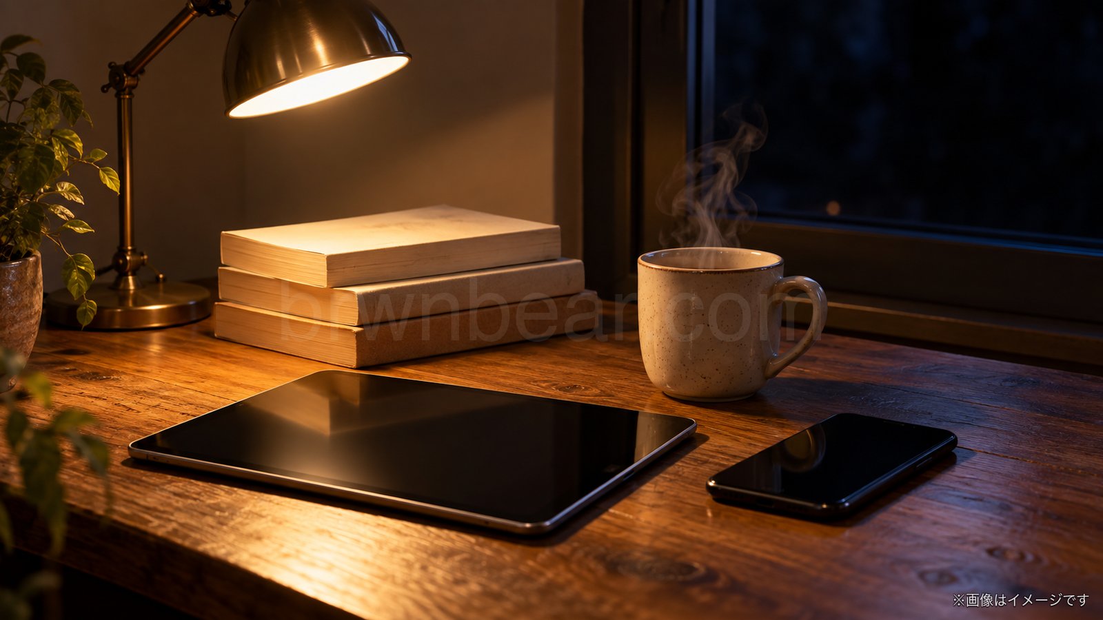 夜のデスクで文庫本とタブレットを用意した読書のイメージ